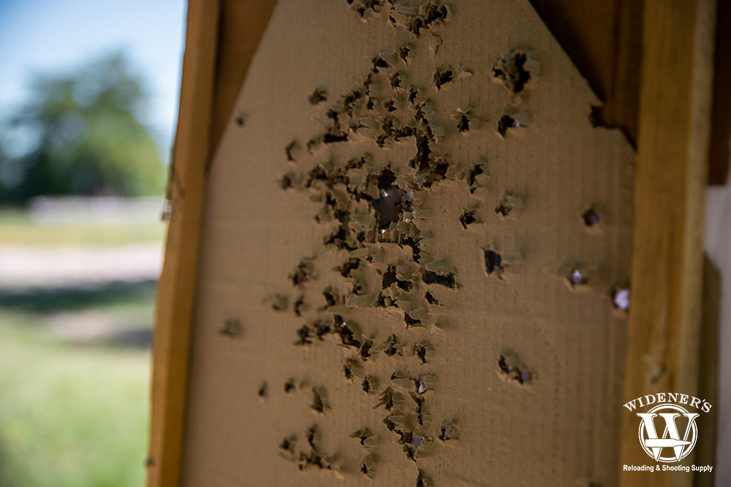 a photo of a carboard target outdoors at a gun range with holes from ball ammo