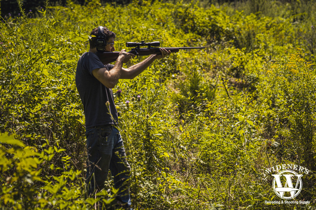 A photo of a man shooting a 30-06 hunting rifle outdoors