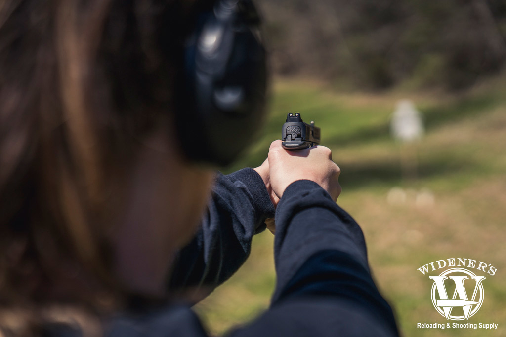 photo of a female competition shooter firing at a steel target outdoors