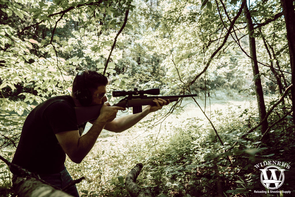 photo of a man in the woods shooting the ruger american rifle chambered in 350 legend