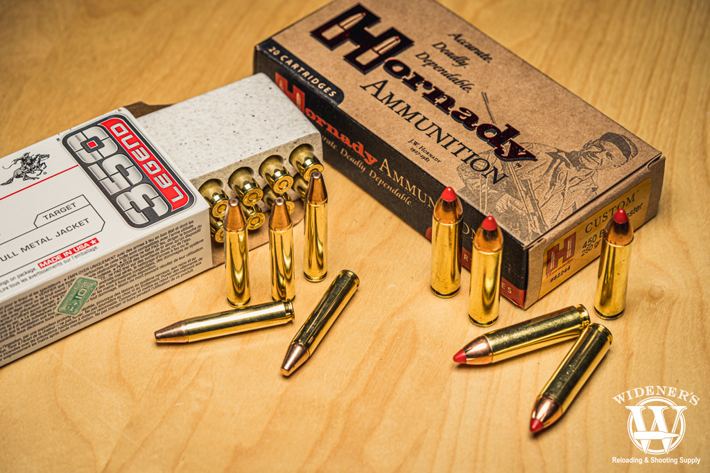A photo of 350 legend ammo next to 450 bushmaster ammo on a sheet of plywood.