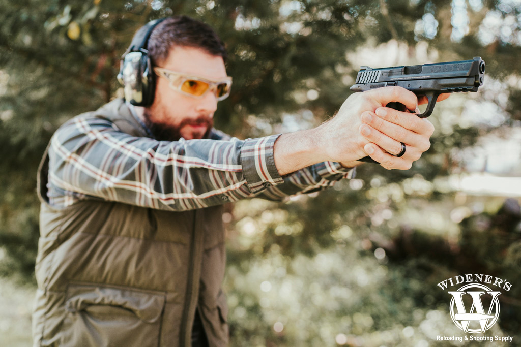 a photo of a man shooting a handgun outdoors