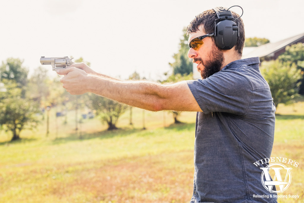 a photo of a man shooting a revolver outdoors