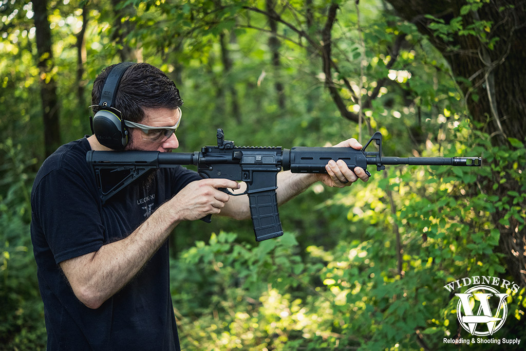 a photo of a man shooting an ar-15 rifle outdoors