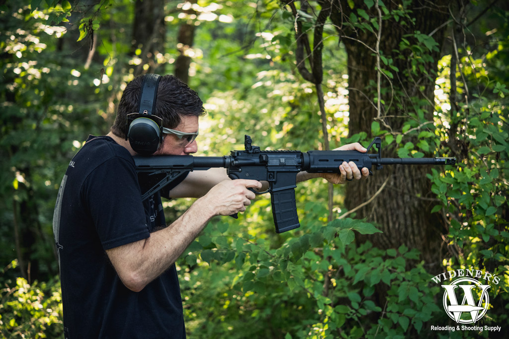 a photo of a man shooting an ar-15 rifle outdoors