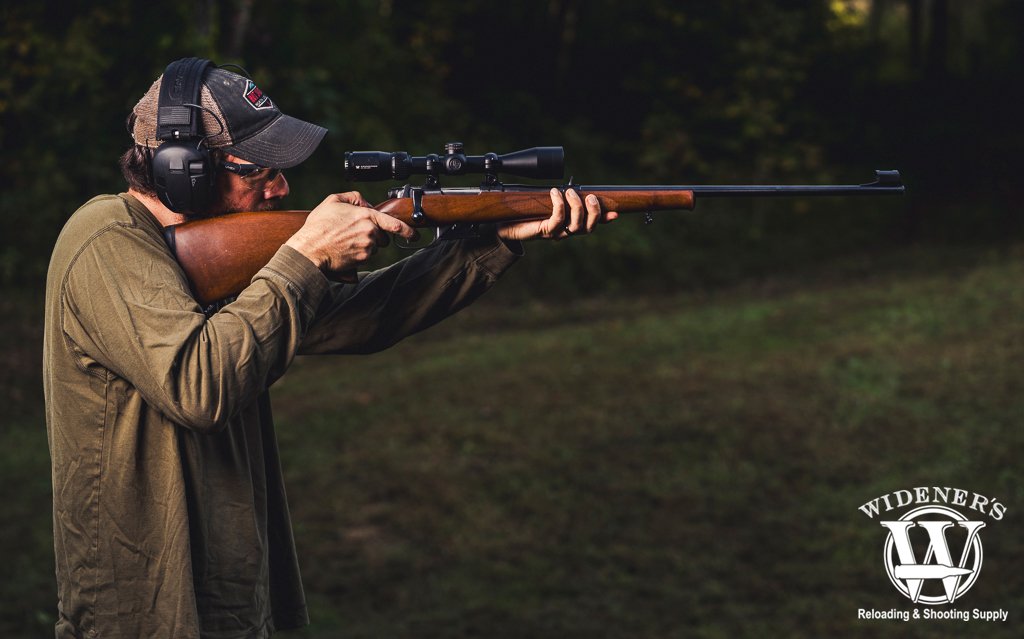 a photo of a man shooting a rifle outdoors