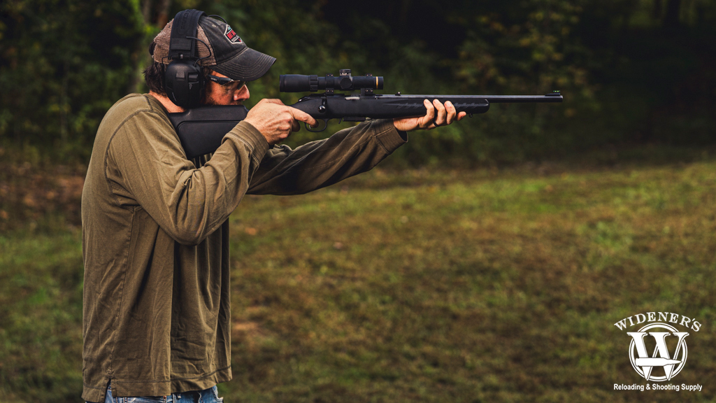 a photo of a man shooting a rimfire rifle outdoors
