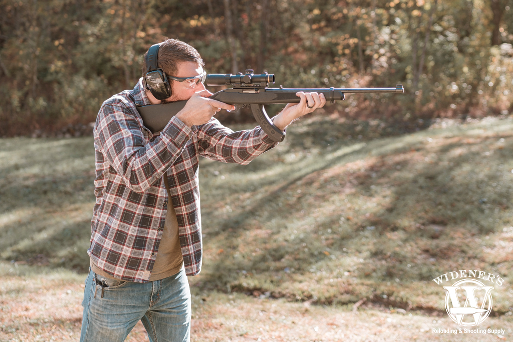 a photo of a man shooting a gun outdoors