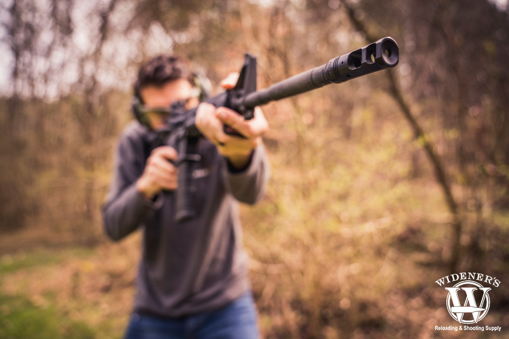 a man shooting a rifle in the woods