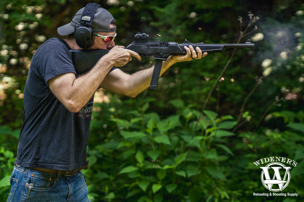 a photo of a man shooting a carbine rifle outdoors