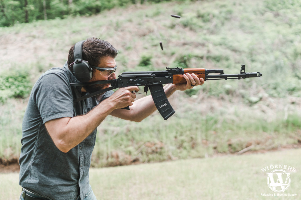 a photo of a man shooting an ak74 rifle outdoors