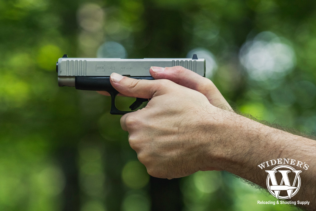 a photo of a man shooting a glock 48 9mm pistol outdoors