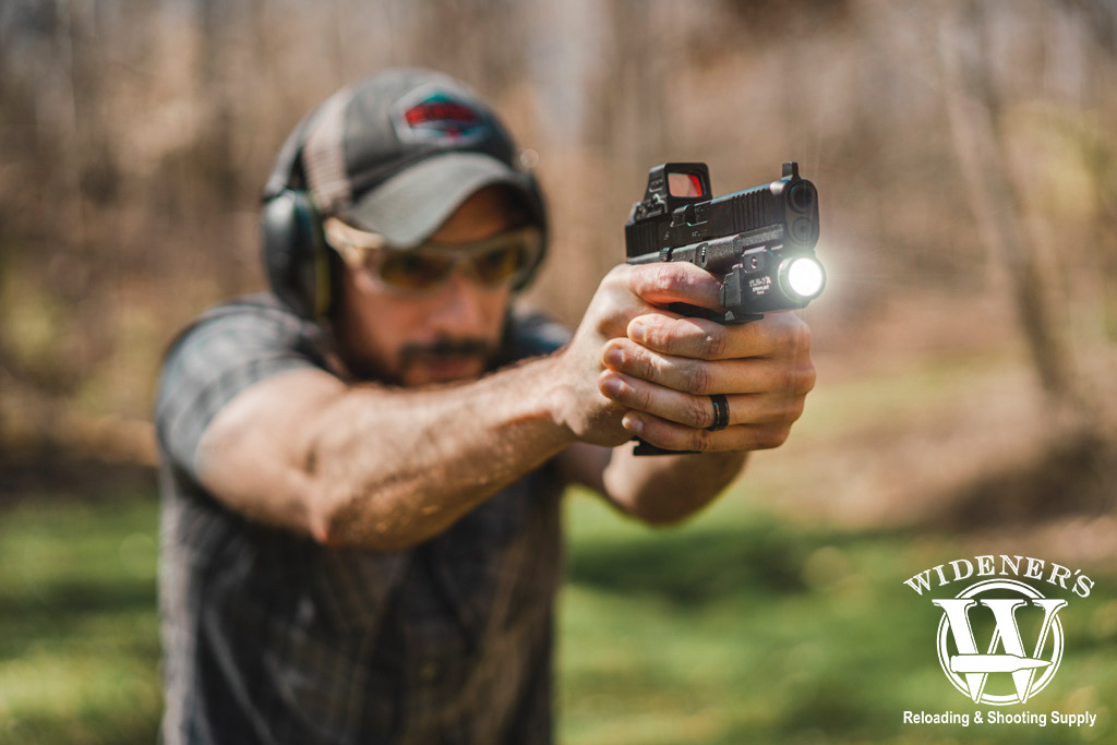 a photo of a man shooting a glock handgun outdoors