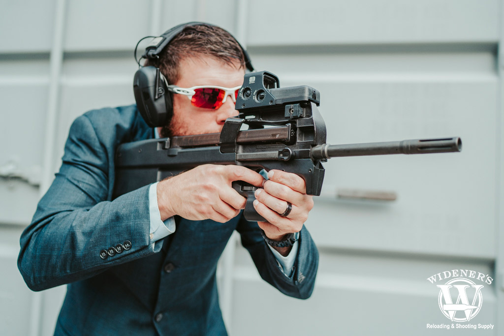 a photo of a sharp dressed man shooting an fn ps90 gun 