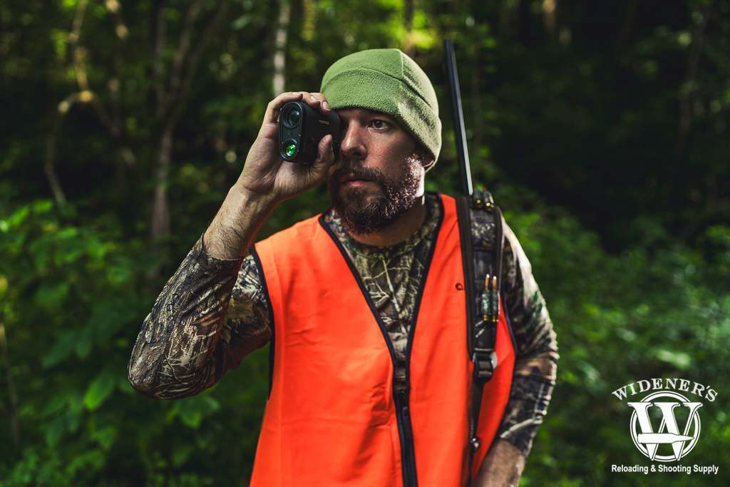 a photo of a man hunting in the woods with a range finder