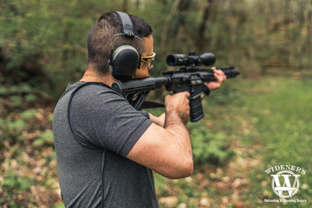 a photo of a man shooting an ar-10 rifle outdoors