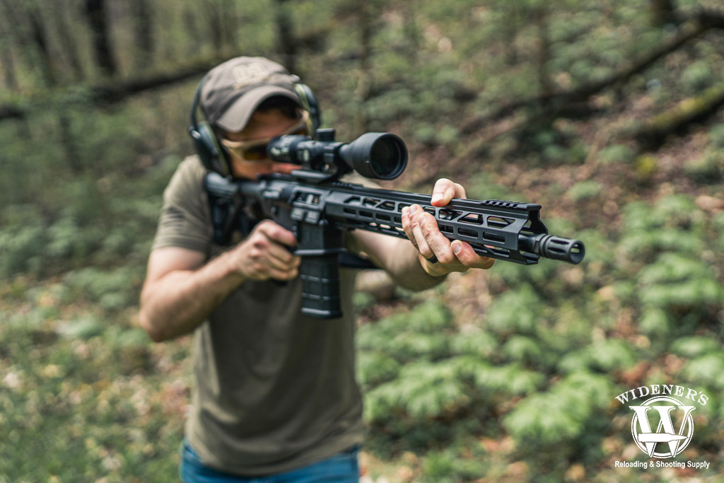 a photo of a man shooting an ar-10 rifle at an outdoor range