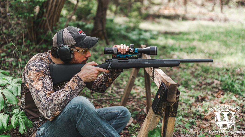 a photo of a man shooting a bolt-action rifle outdoors 