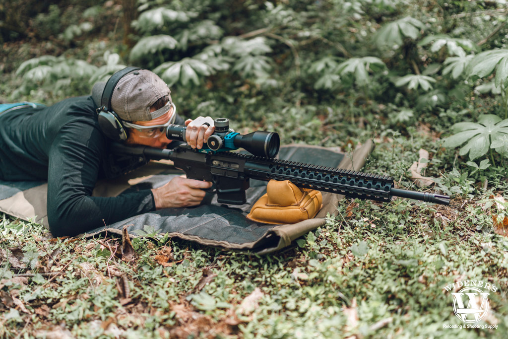a photo of a man shooting a semi-auto rifle outdoors