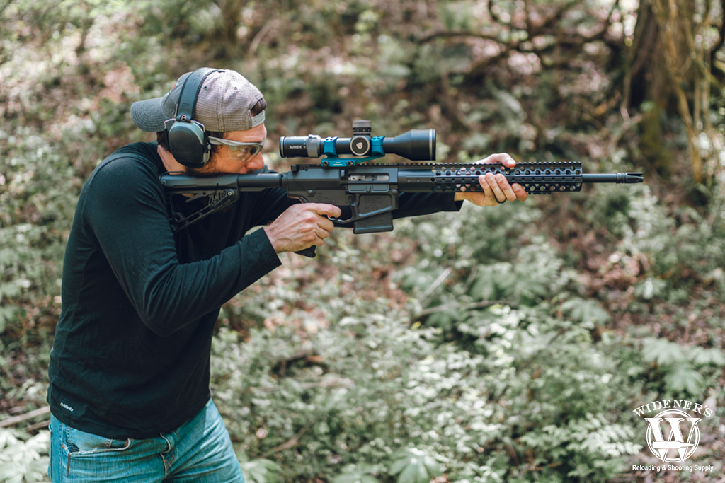 a photo of a man shooting an ar-10 battle rifle outdoors