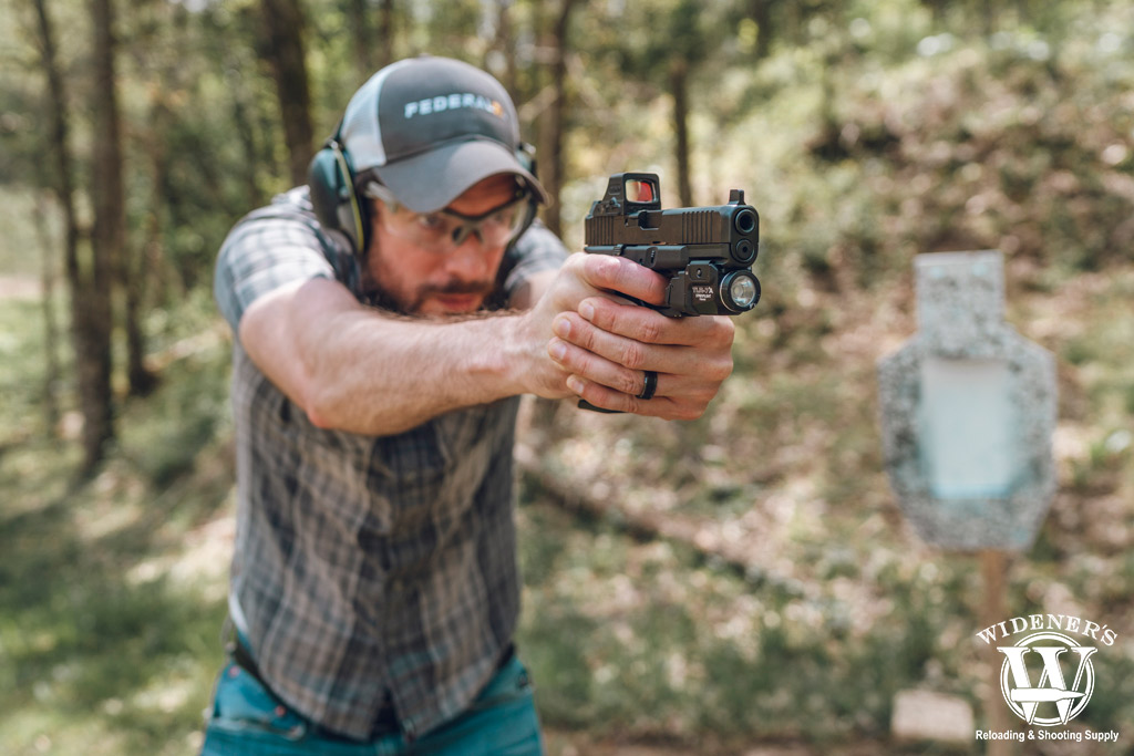 a photo of a man shooting a glock 45 handgun outdoors