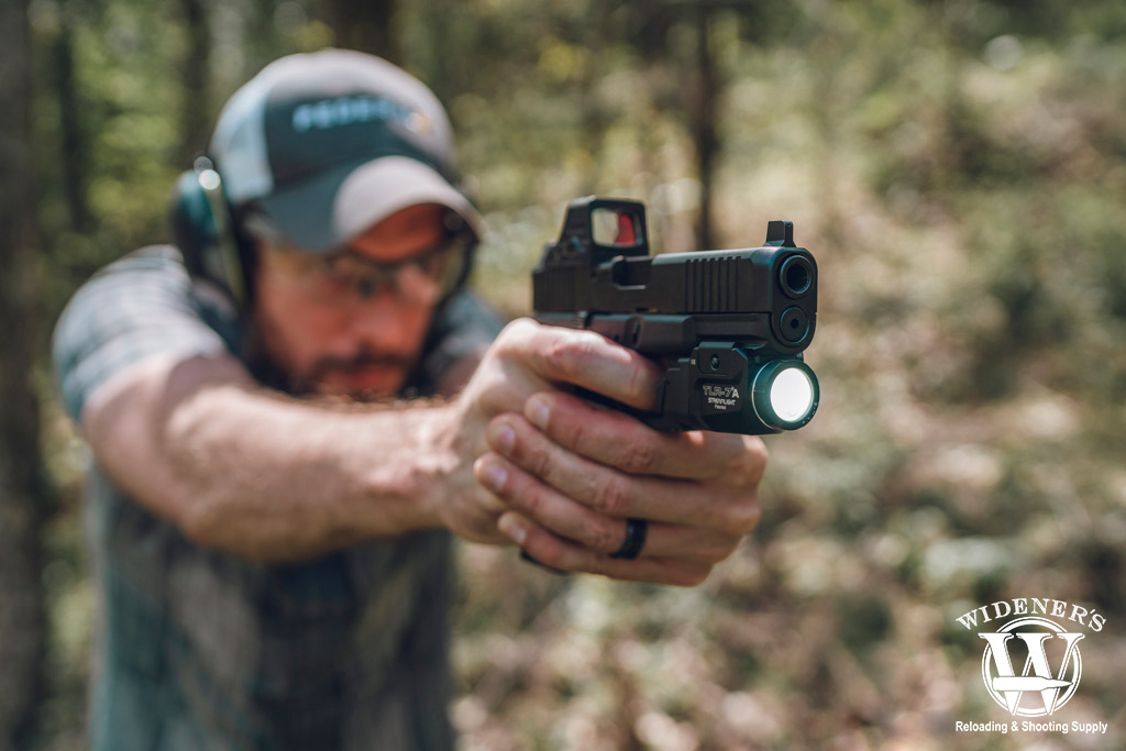 a photo of a man shooting a Glock 45 handgun outdoors