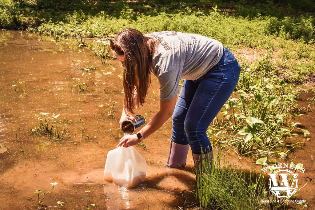 a photo of a woman gathering water for testing in a rubber bladder