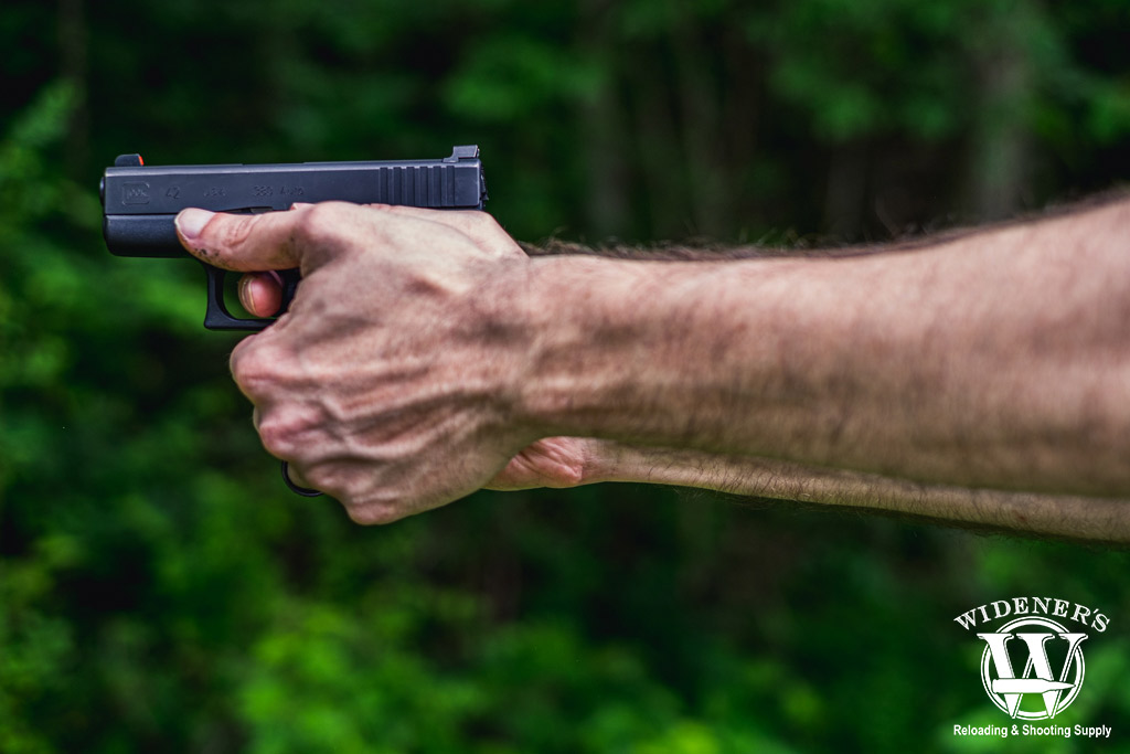 a photo of a man shooting a glock handgun outdoors