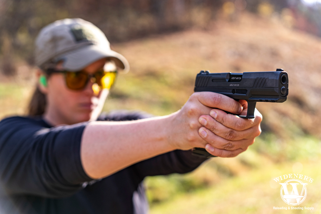 a photo of a woman shooting a handgun outdoors