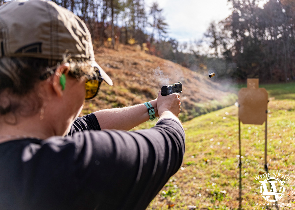 a photo of a woman shooting a handgun at cardboard targets