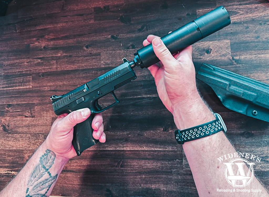 a photo of a man attaching a suppressor to a handgun