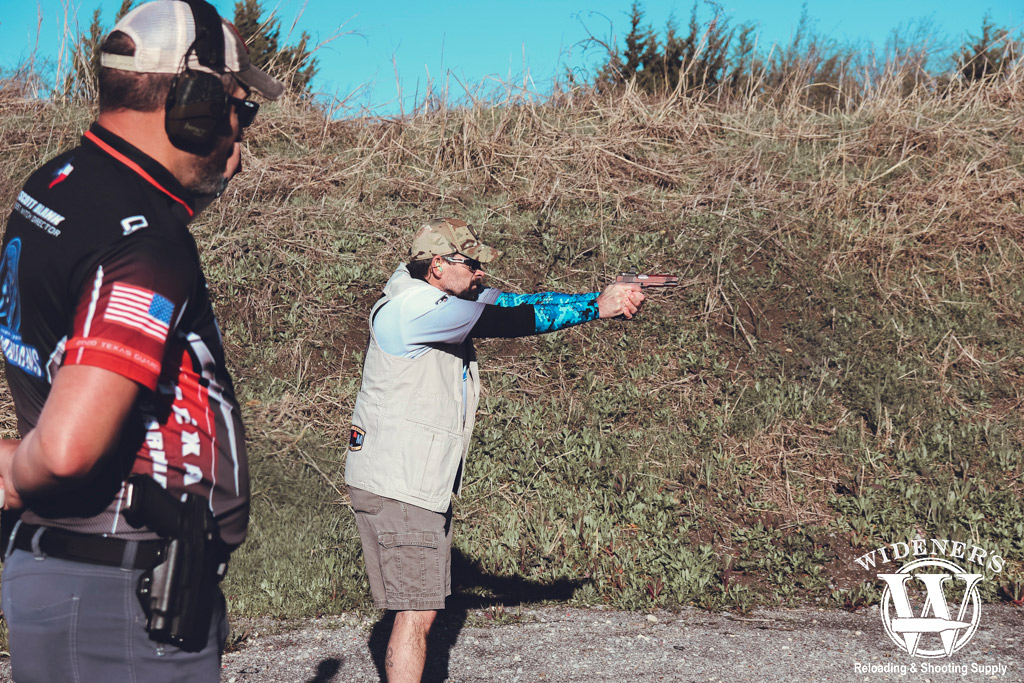 a photo of a man shooting at an idpa competition