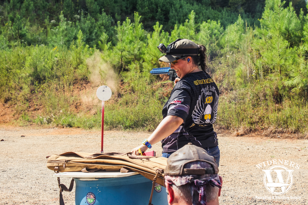 a photo of a female competition shooter reloading at a stage match