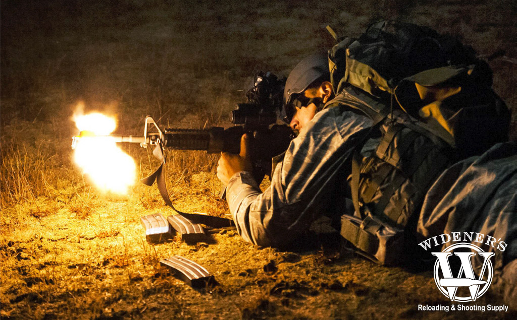 a photo of a us soldier shooting an m4 carbine with muzzle flash