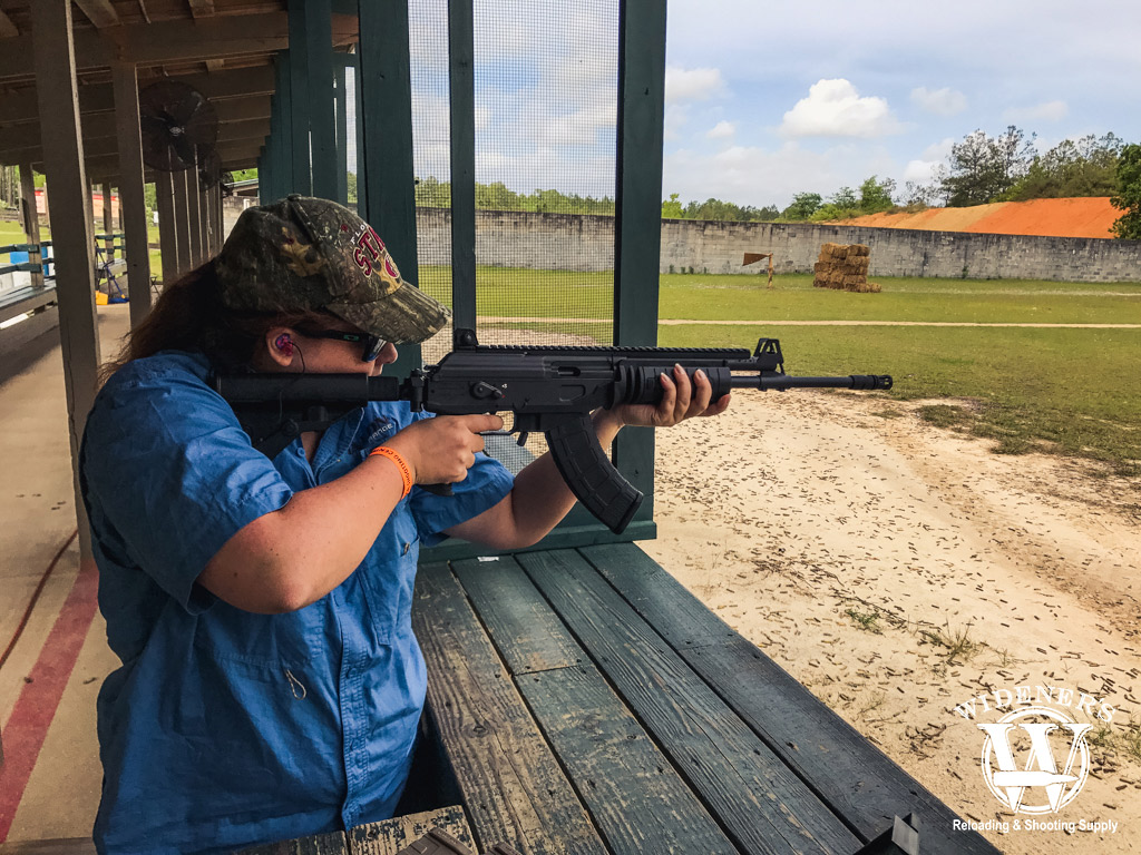 a photo of a woman shooting a rifle with iron sights at a gun range