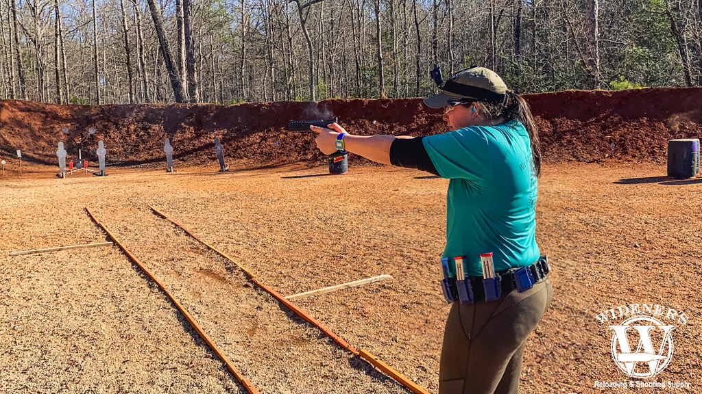 a photo of a female shooting a competition pistol outdoors