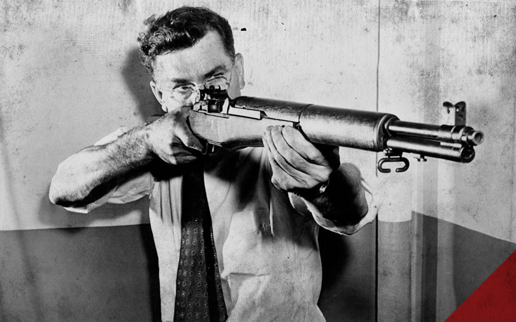 a historical photo of John C. Garand holding his invention