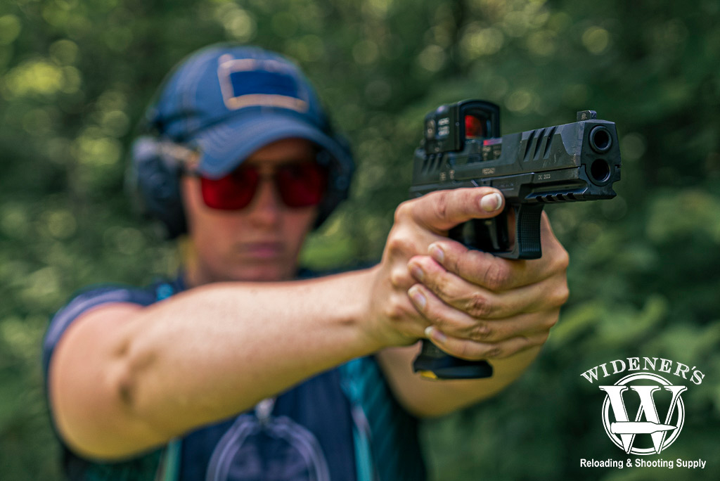 a photo of a woman shooting a handgun with a closed emitter red dot optic